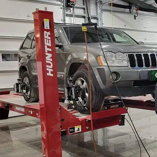 Tires & Alignments in Blowing Rock, NC. Image of a car lifted inside the repair shop receiving a wheel alignment.