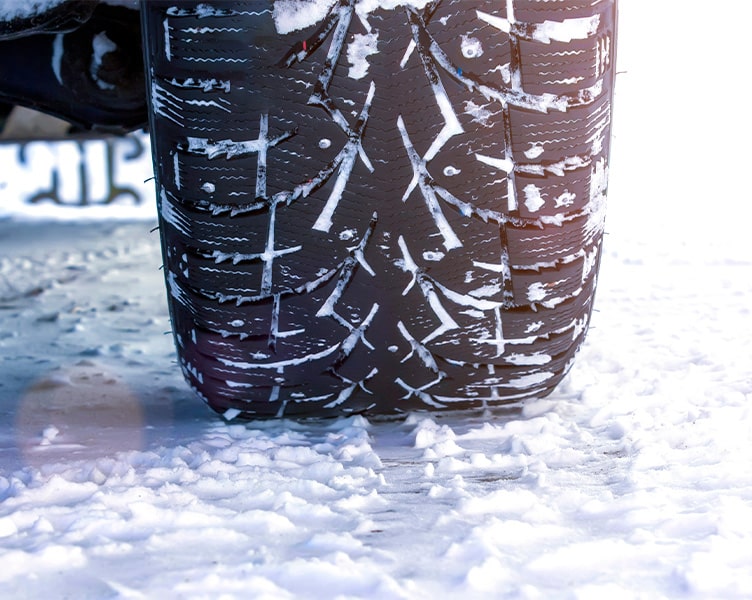 Snow Tires vs. All-Season Tires | L&N Performance Auto | Blowing Rock, NC. Image of driving car closeup of tire with snow on roads and tire treads.