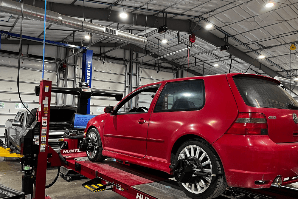 wheel alignment, auto repair in Blowing Rock, NC at L&N Performance Auto Repair. Red Volkswagen Golf R32 on a Hunter alignment rack inside a well-lit auto repair shop, with another vehicle being serviced in the background.