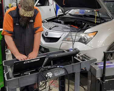 Digital Vehicle Inspection in Blowing Rock, NC At L&N Performance. Image of Mechanic using a diagnostic laptop during a vehicle inspection with an open hood